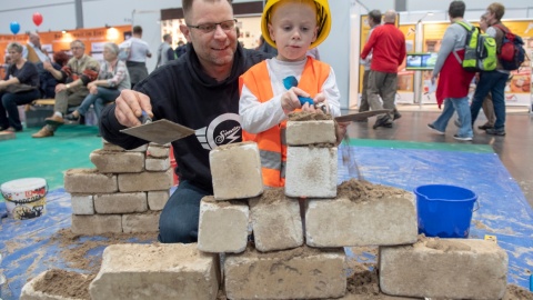 Ein Vater braut mit seinem Kind eine Mauer aus Stein.