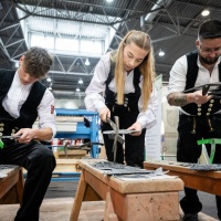 3 Handwerker:innen arbeiten an einer Schieferntafel.